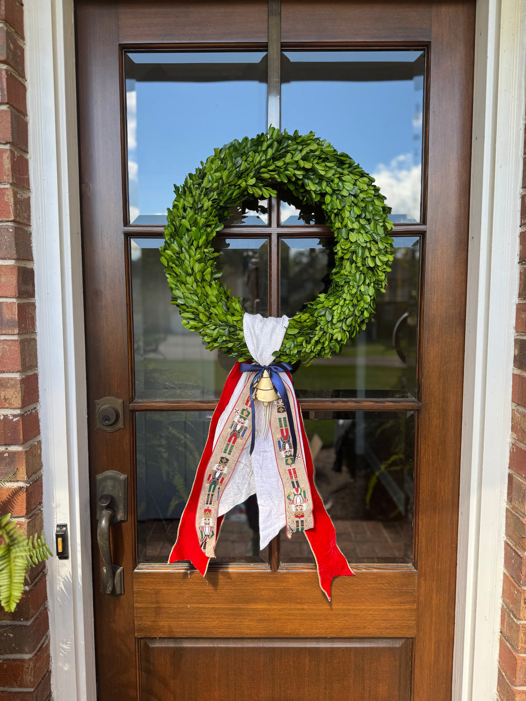 Boxwood wreath with Christmas sash and a wreath ornament