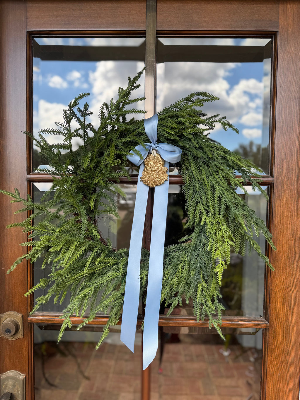 Cedar wreath with light blue ribbon and a gold wreath sash ornament 